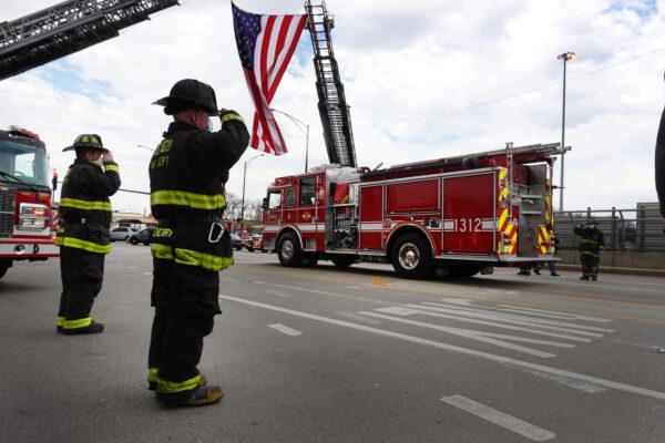 Firefighters salute as a funeral procession passes by, carrying the remains of firefighter Edward Singleton, a 33-year veteran of the Chicago Fire Department, in Chicago on April 22, 2020. Singleton died from complications from COVID-19. (Scott Olson/Getty Images)