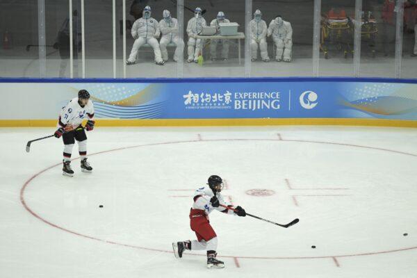 Athletes take part in an ice hockey training session as health workers (top) stand by during a 2022 Beijing Winter Olympic Games test event, at the National Indoor Stadium in Beijing on Nov. 11, 2021. (Wang Zhao/AFP via Getty Images)