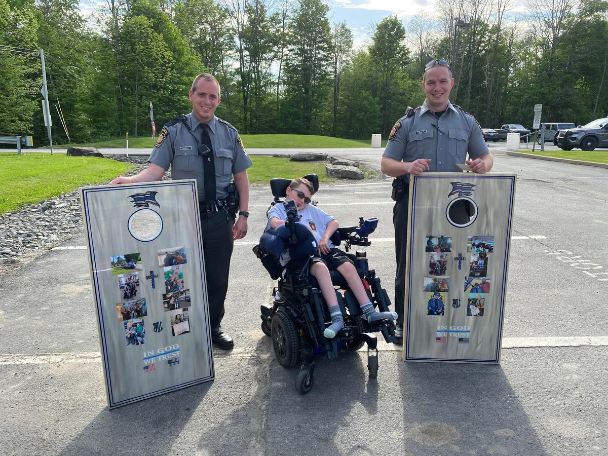 Josh with a cornhole game set that he made with the help of his mom to bless the Gibson state police officers with. The boards have different photos of Josh with police officers. (Courtesy of <a href="https://www.facebook.com/rebecca.bourassa.3">Rebecca Bourassa</a>)