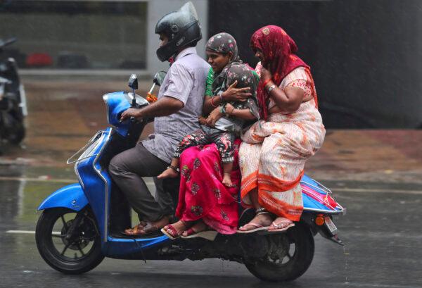 People ride a motorcycle in the rain in Hyderabad, India on Nov. 20, 2021. (Mahesh Kumar A./AP Photo)