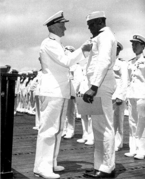 Recognition of the brave enlisted blacks helped pave the way for the Civil Rights movement in the following decades. Admiral Chester W. Nimitz pins a Navy Cross on Mess Attendant Second Class Miller aboard the USS Enterprise at Pearl Harbor. Official U.S. Navy photograph. (Public Domain)