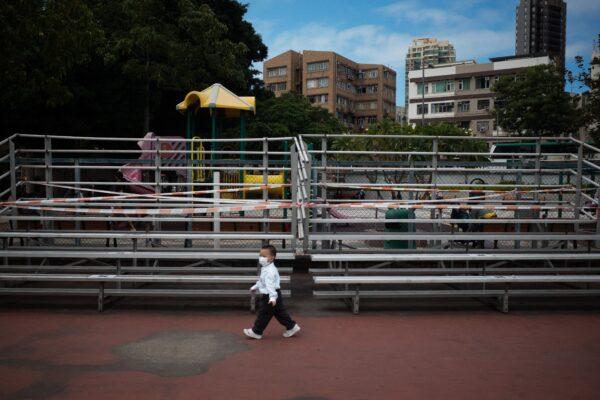 A boy walks past taped-off bleachers amid the COVID-19 pandemic at a playground in Hong Kong on Nov. 9, 2021. (Bertha Wang/AFP via Getty Images)