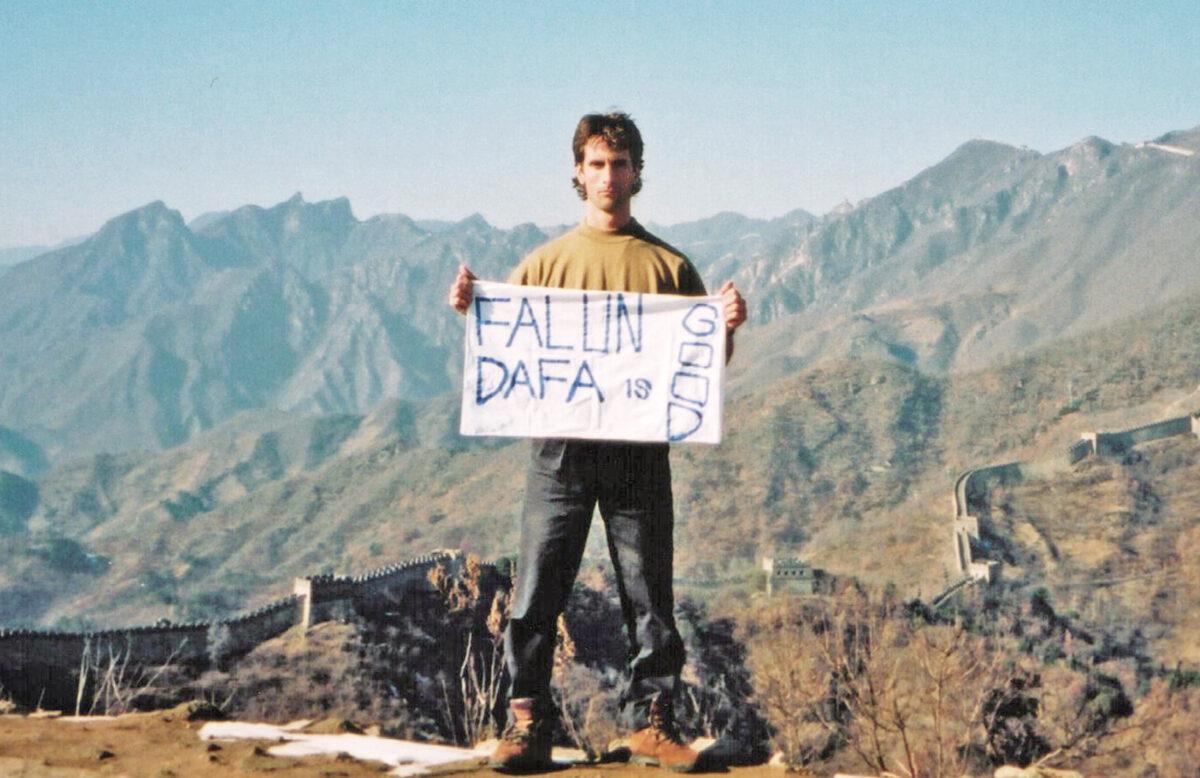 Joel Chipkar on the Great Wall with a sign that he made with materials he found in his hotel room, in Beijing, in November 2001. (Courtesy of Joel Chipkar)