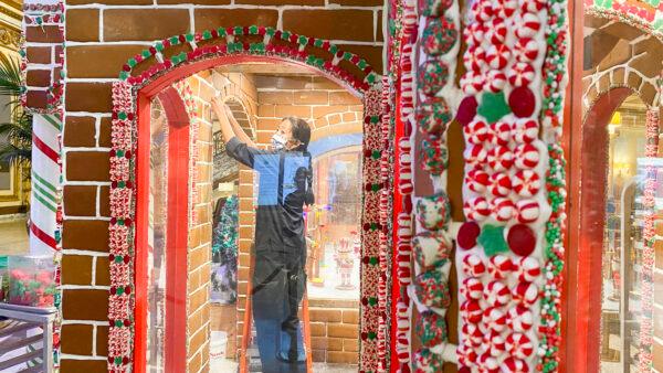 An employee decorates the Gingerbread House with See’s Candies at Fairmont San Francisco on Nov. 18, 2021. (Ilene Eng/The Epoch Times)