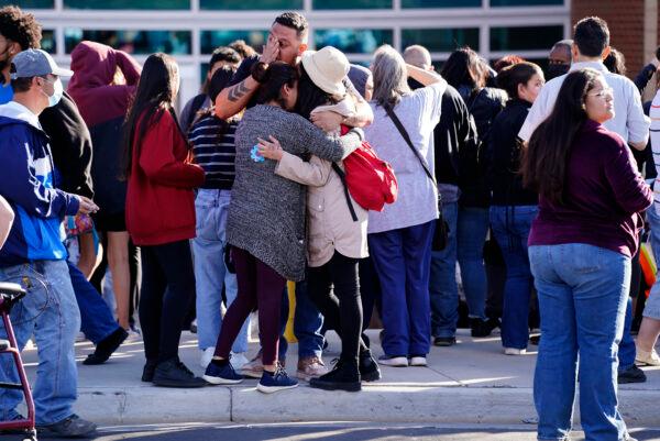 Edgar James, front center, battles with tears as he hugs his daughter, Mia, front right, and his wife, Olga Aguirre, front left, as they are reunited outside Hinkley High School in Aurora, Colo., on Nov. 19, 2021. (Philip B. Poston/Sentinel Colorado via AP)