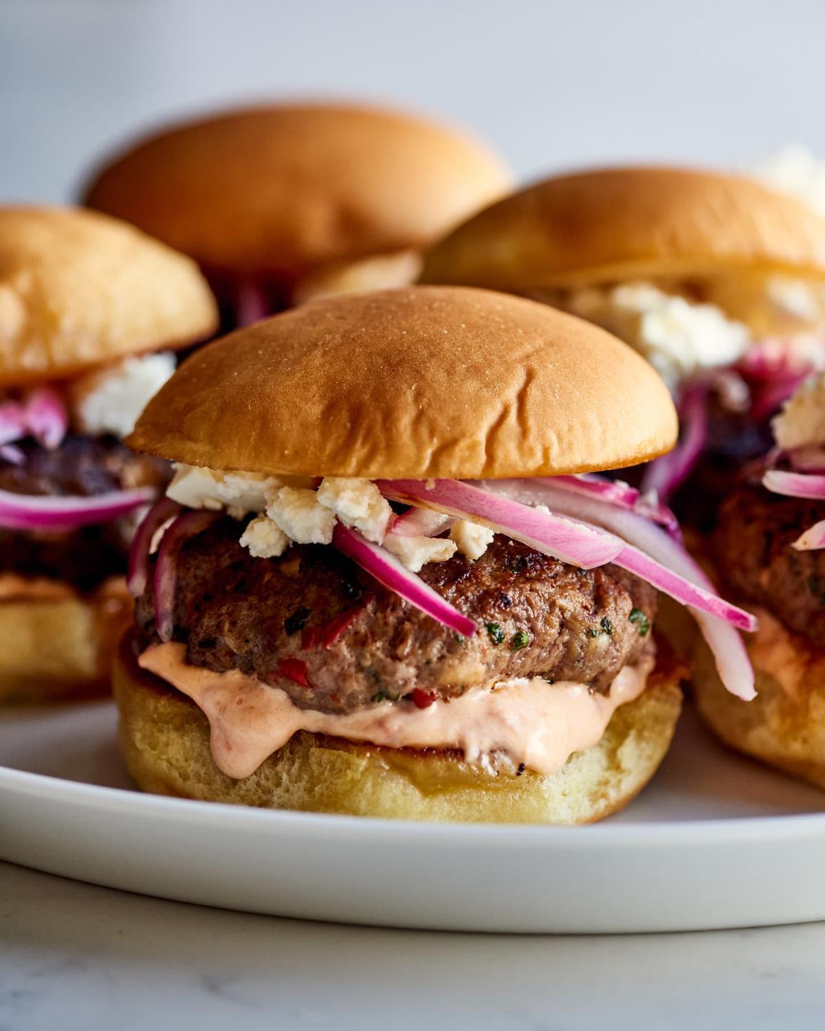 Harissa and lamb make for a dynamic duo in these sliders topped with feta cheese, pickled onions and harissa mayo. (Joe Lingeman/TNS)