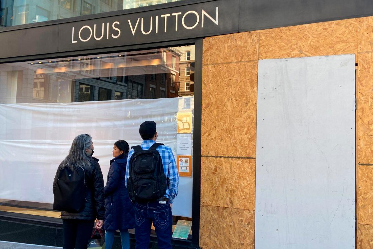 Union Square visitors look at damage done to a Louis Vuitton store in San Francisco on Nov. 21, 2021. (Danielle Echeverria/San Francisco Chronicle via AP)