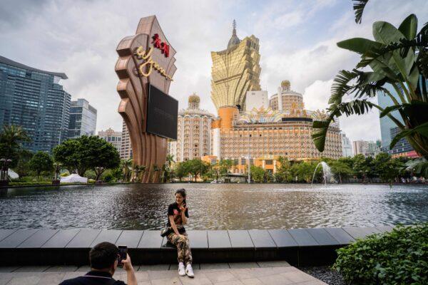 Visitors take photos outside the Wynn casino resort with a view of the Grand Lisboa (top C) casino resort building in Macau, China, on March 5, 2019. (Anthony Wallace/AFP via Getty Images)