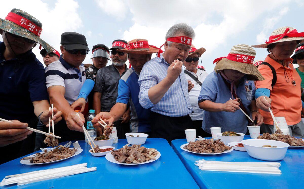 Members of Korean Dog Meat Association eat dog meat during a rally to support eating dog meat in front of the National Assembly in Seoul, South Korea on July 12, 2019. (Ahn Young-joon/AP Photo)