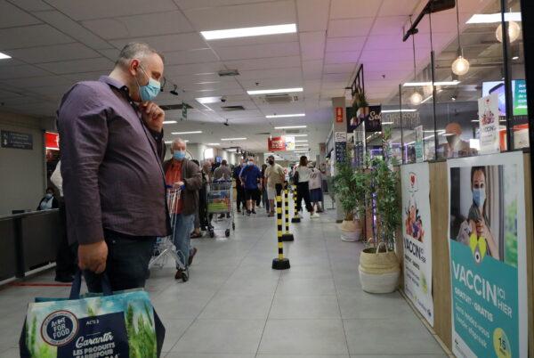 A shopper, wearing a face mask, looks at a poster for a COVID-19 vaccination center installed inside a supermarket in Brussels, on Aug. 30, 2021. (Bart Biesemans/Reuters)