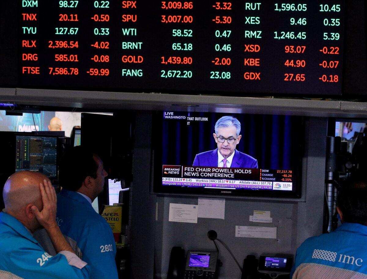 Traders look on as a screen shows Federal Reserve Chairman Jerome Powell's press conference after the Federal Reserve interest rates announcement on the floor of the New York Stock Exchange (NYSE) on July 31, 2019. (Brendan McDermid/Reuters)