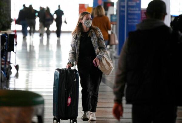A traveler wears a protective face covering while heading to the American Airlines check-in counter as the Thanksgiving Day holiday approaches at the Denver International Airport on Nov. 23, 2021. (David Zalubowski/AP Photo)