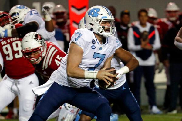 North Carolina quarterback Sam Howell (7) rolls out while being chased by North Carolina State defensive tackle Davin Vann (45) during the first half of an NCAA college football game in Raleigh, N.C., on Nov. 26, 2021. (Chris Seward/AP Photo)