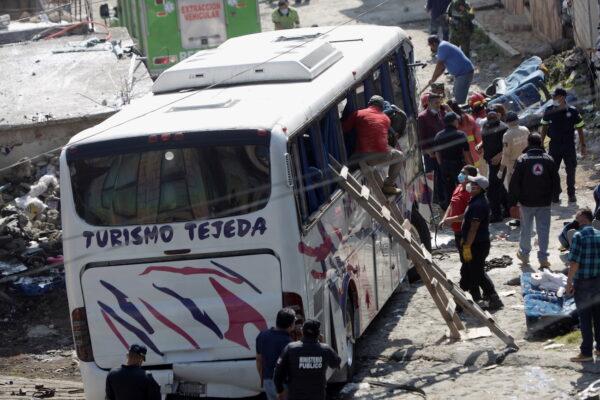 Government personnel work at a scene where at least 19 people were killed and 20 more injured after a passenger bus traveling on a highway crashed into a house, according to authorities, in San Jose El Guarda, Mexico, Nov. 26, 2021. (Luis Cortes/Reuters)