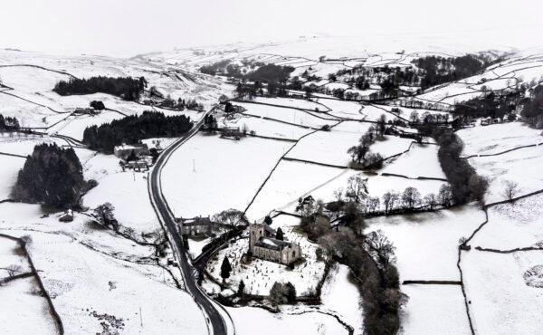 Snow covers fields and hills surrounding St, Mary The Virgin Church in the Arkengarthdale, North Yorkshire, amid freezing conditions in the aftermath of Storm Arwen, on Nov. 28, 2021. (Danny Lawson/PA via AP)