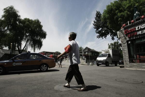 An elderly woman wearing a red arm badge patrols a street on July 17, 2008 in Beijing, China. (Guang Niu/Getty Images)
