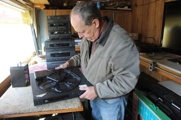 Joe Spanel examines a carousel CD player, on Nov. 28, that longtime customer Tony Wilson hopes to have fixed. Wilson, 70, has been coming into the shop for 50 years. (Michael Sakal/The Epoch Times)