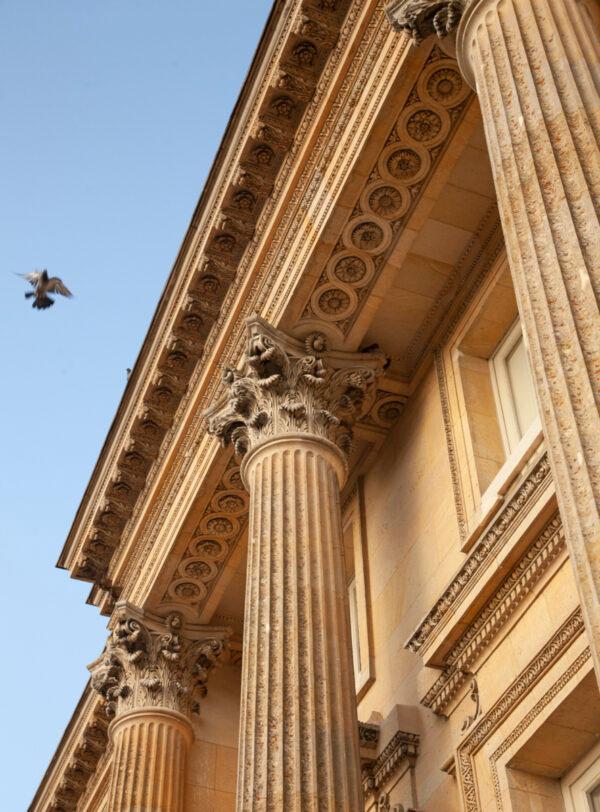 As one draws closer to the building, the window and cornice ornamentation and the Corinthian column capitals (crowns) become prominent and invite one to admire the refined design and craftsmanship. (J.H.Smith/Cartio)