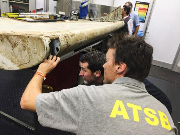 Staff from the Australian Transport Safety Bureau examine a piece of aircraft debris that is highly likely to have come from flight MH370 at their laboratory in Canberra, Australia, on July 20, 2016. (ATSB via AP, File)