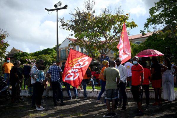 Protestors hold flags of the 'Confederation Generale du Travail de la Guadeloupe' CGTG Trade union as they demonstrate against compulsory vaccination in front of the sub-prefecture of Pointe-a-Pitre, in the French Caribbean island of Guadeloupe, on Nov. 29, 2021. (Christophe Archambault/AFP via Getty Images)