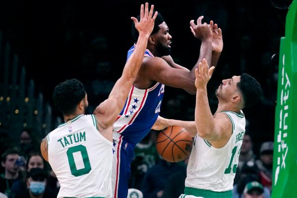 Philadelphia 76ers center Joel Embiid, center, loses control of the ball against Boston Celtics center Enes Kanter Freedom, right, and forward Jayson Tatum (0) during the first half of an NBA basketball game, in Boston, on Dec. 1, 2021. (Charles Krupa/AP Photo)