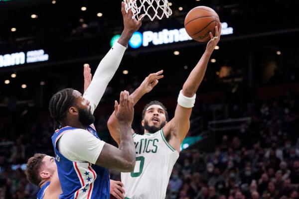 Boston Celtics forward Jayson Tatum (0) drives to the basket against Philadelphia 76ers center Andre Drummond (L) during the first half of an NBA basketball game, in Boston on Dec. 1, 2021. (Charles Krupa/AP Photo)