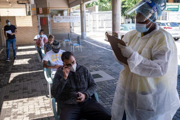 A healthcare worker helps a patient to fill out a form before conducting a PCR Covid-19 test at the Lancet laboratory in Johannesburg on November 30, 2021. (EMMANUEL CROSET/ Getty Images)