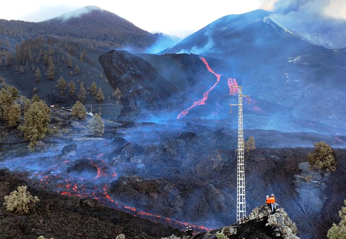 Scientists with the Canary Islands' volcanology institute, Involcan, inspect as the lava flows from a volcano on the Canary island of La Palma, Spain, on Oct. 30, 2021. (Emilio Morenatti/AP Photo)
