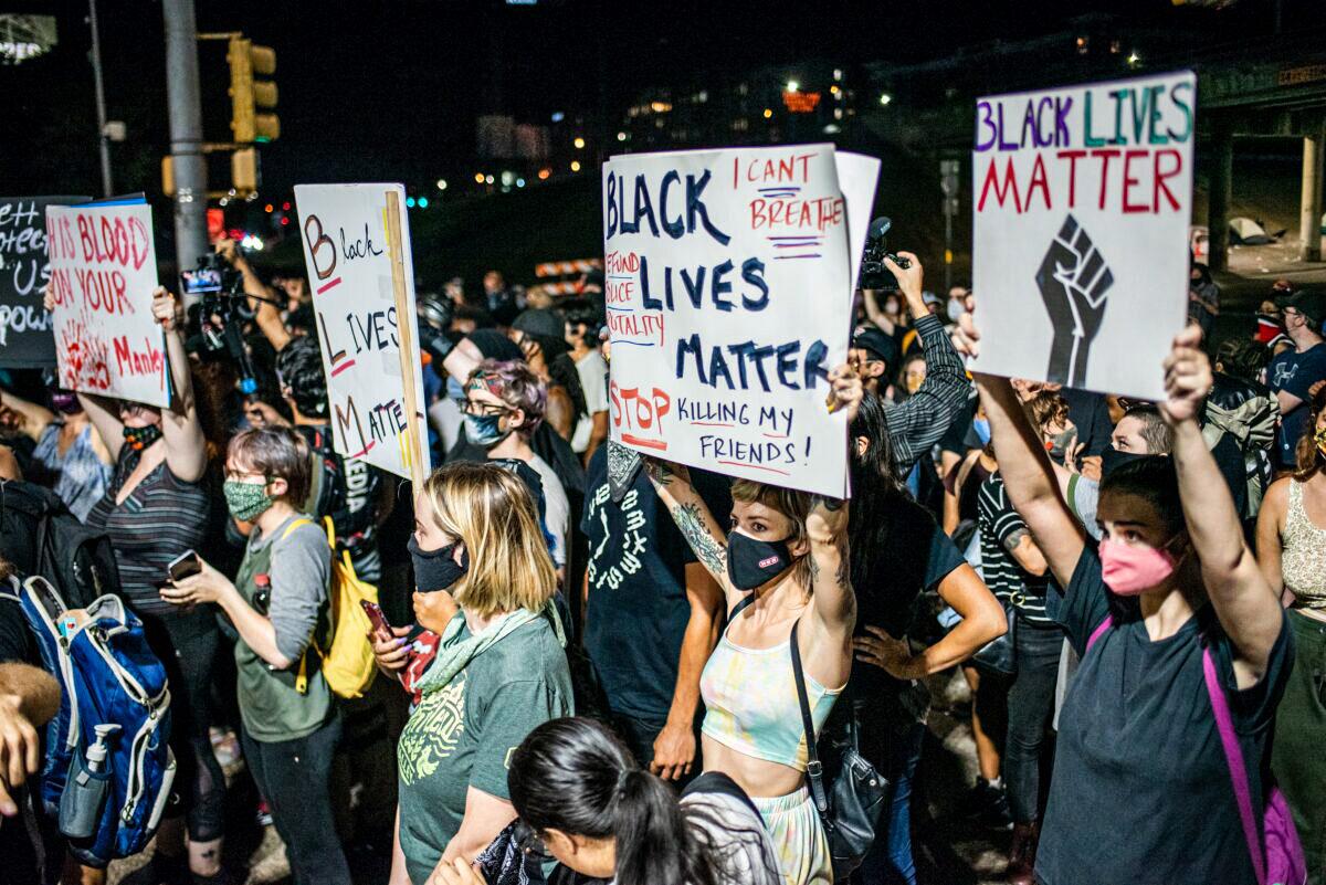 People hold up signs outside Austin Police Department after a vigil for Garrett Foster, a Black Lives Matter protester who was shot dead after allegedly brandishing his firearm at a driver, in Austin, Texas, on July 26, 2020. (Sergio Flores/Getty Images)