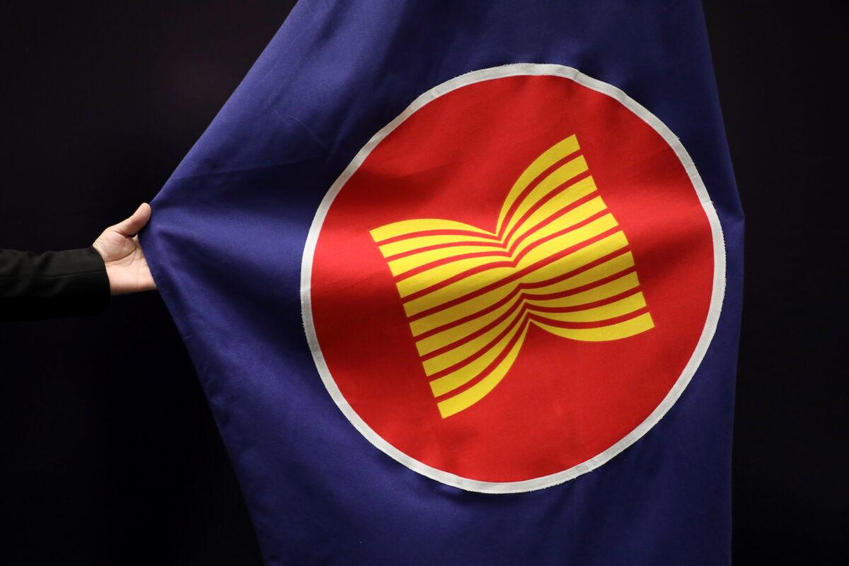 A worker adjusts an ASEAN flag at a meeting hall in Kuala Lumpur, Malaysia, on Oct. 28, 2021. (Lim Huey Teng/Reuters)