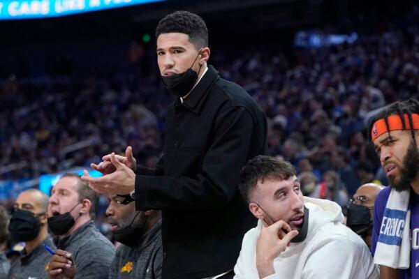 Injured Phoenix Suns guard Devin Booker applauds from the bench during the first half of an NBA basketball game against the Golden State Warriors in San Francisco, on Dec. 3, 2021. (Jeff Chiu/AP Photo)