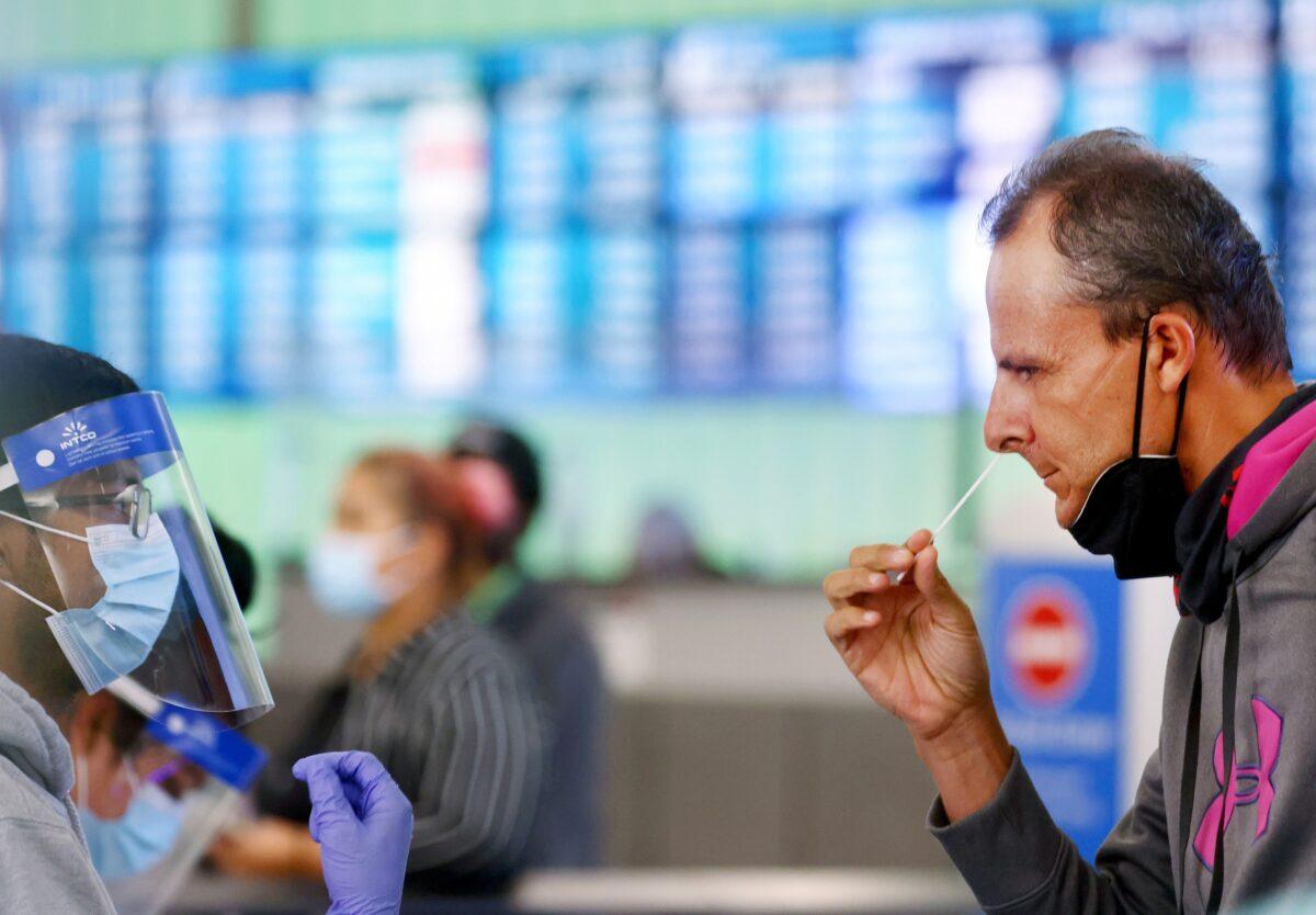 A passenger who arrived from Italy administers a self-collected nasal swab on the first day of a new rapid COVID-19 testing site for arriving international passengers at Los Angeles International Airport on Dec. 3, 2021. (Mario Tama/Getty Images)