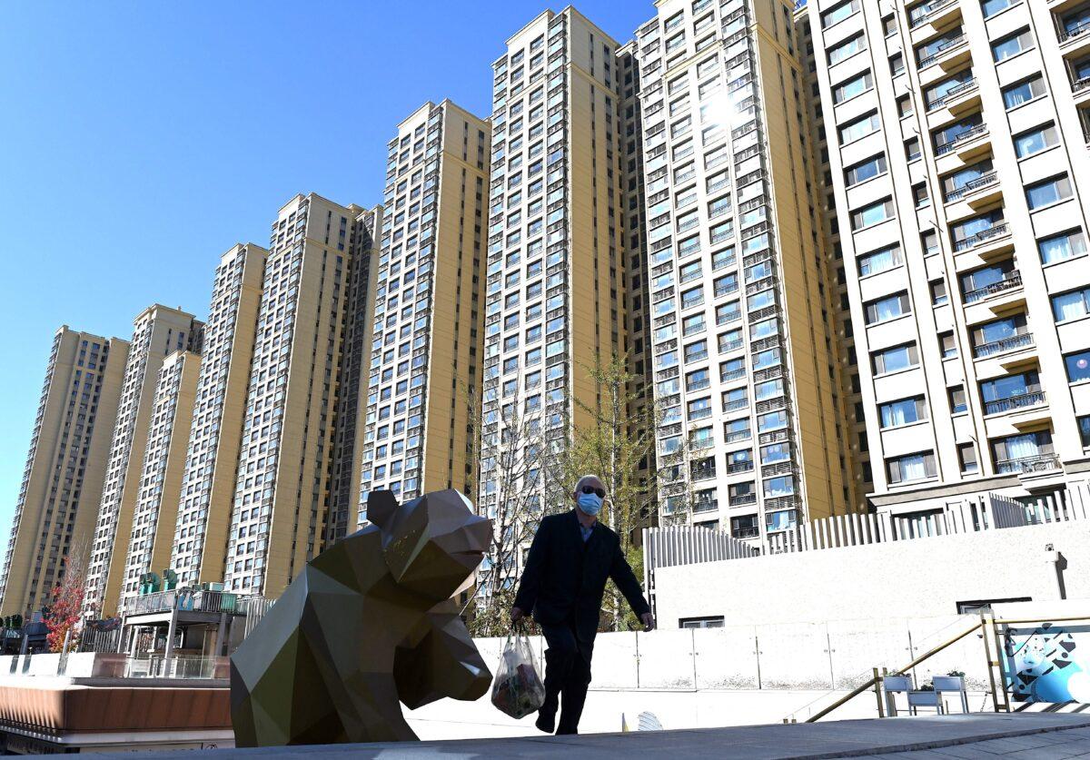 A man walks in front of a housing complex by Chinese property developer Evergrande in Beijing on Oct. 21, 2021. (Noel Celis/AFP via Getty Images)