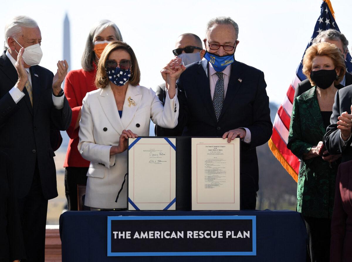 Speaker of the House Nancy Pelosi and Senate Majority Leader Chuck Schumer hold the signed American Rescue Plan Act after the House Chamber voted on the final revised legislation of the $1.9 trillion COVID-19 relief plan, at the U.S. Capitol on March 10, 2021. (OLIVIER DOULIERY/Getty Images)