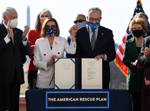 Speaker of the House Nancy Pelosi and Senate Majority Leader Chuck Schumer hold the signed American Rescue Plan Act after the House Chamber voted on the final revised legislation of the $1.9 trillion Covid-19 relief plan at the U.S. Capitol, on Mar. 10, 2021. (Olivier Douliery/Getty Images)