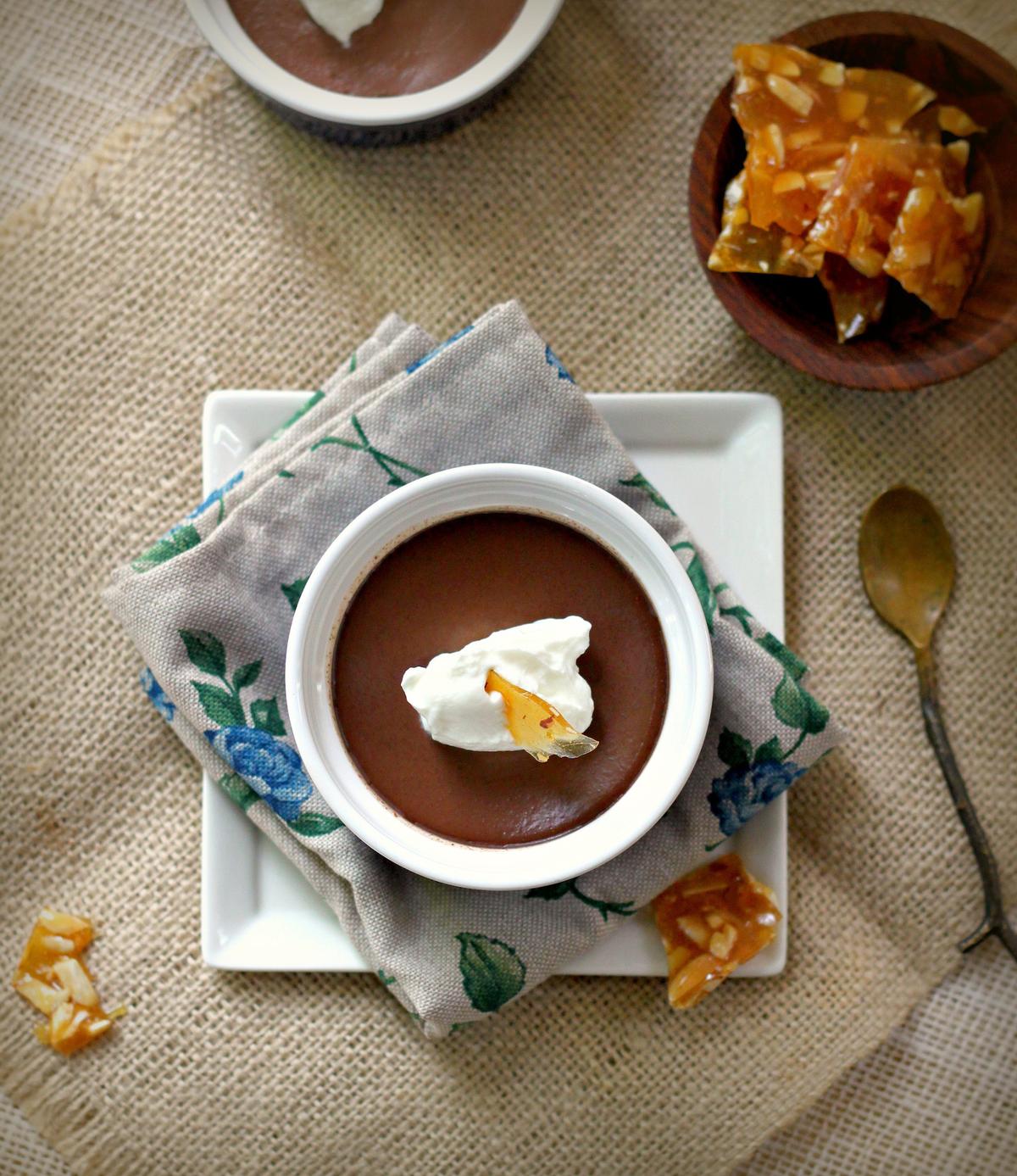 These chocolate custards get dressed up for the holidays with an infusion of hazelnuts and Frangelico, Frangelico-laced whipped cream, and shards of hazelnut praline. (Lynda Balslev for Tastefood)