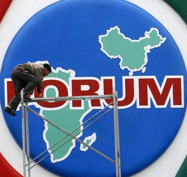 A worker tries to get on a scaffold to install decorations promoting the Beijing Summit of the Forum on China-Africa Cooperation (FOCAC) at the Tiananmen Square in Beijing, China, on Oct. 27, 2006. (China Photos/Getty Images)