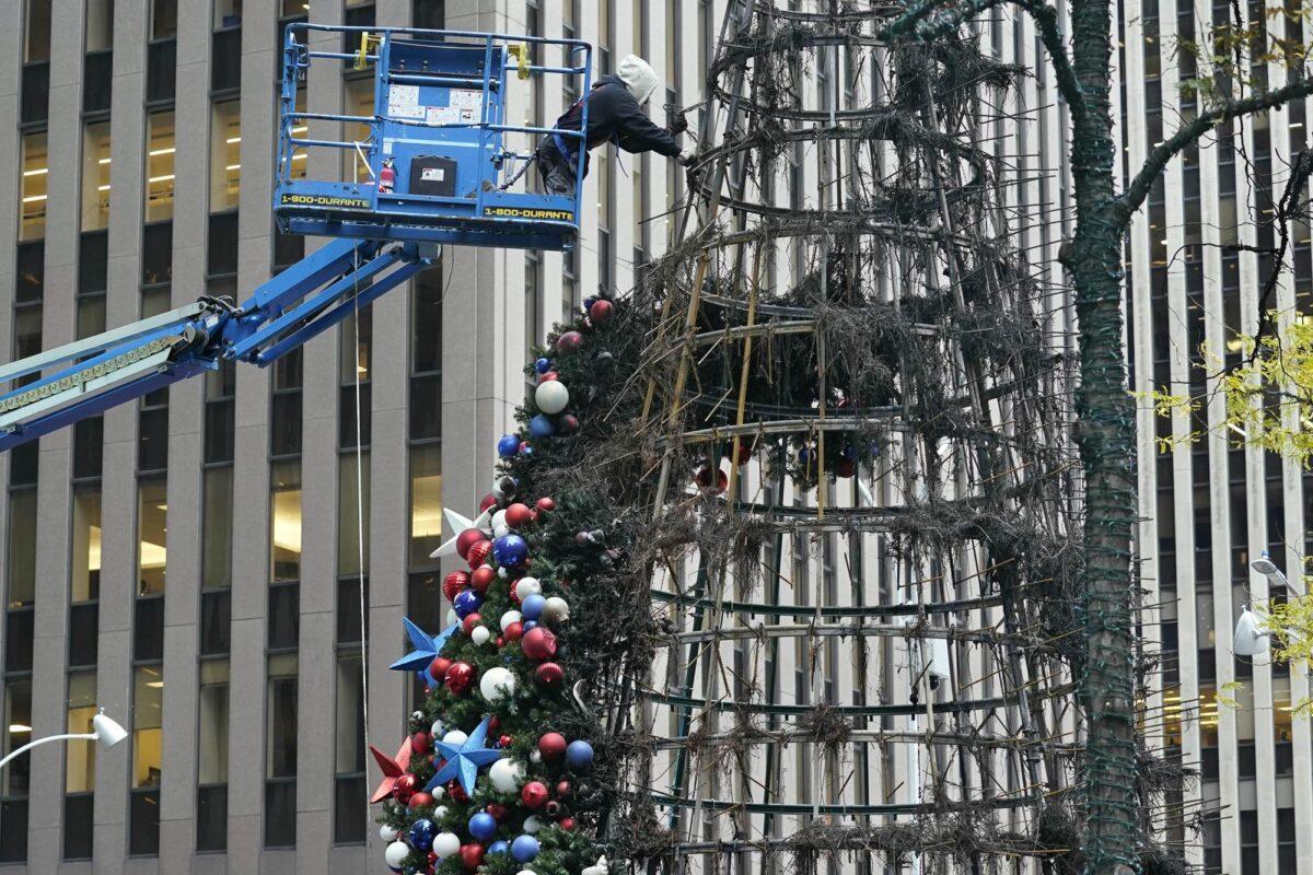 A worker disassembles a Christmas tree outside Fox News headquarters, in N.Y.C., on Dec. 8, 2021. (Richard Drew/AP Photo)