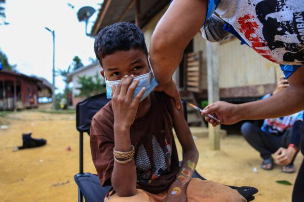 A teenage boy receives a dose of the Pfizer vaccine in Pos Simpor, a village and settlement of Orang Asli (indigenous Malaysians) in the district of Gua Musang, Kelantan, Malaysia, on Oct. 5, 2021. (Annice Lyn/Getty Images)