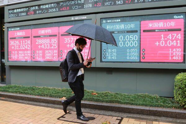 A man walks by an electronic stock board of a securities firm in Tokyo, Japan, on Dec. 8, 2021. (Koji Sasahara/AP Photo)