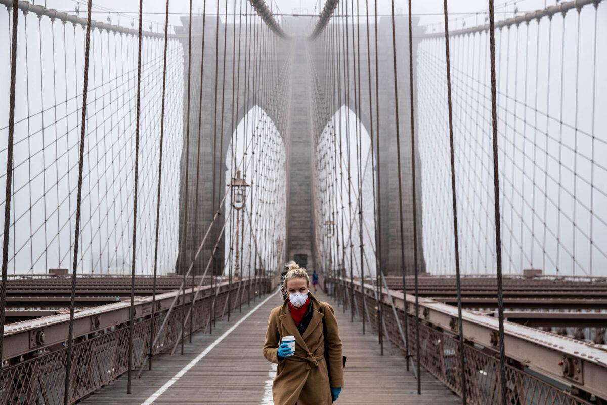A woman wearing a mask walks the Brooklyn Bridge in the midst of the coronavirus (COVID-19) outbreak in New York City on March 20, 2020. (Victor J. Blue/Getty Images)