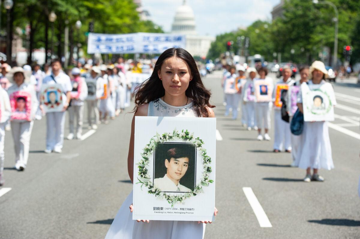 A woman holds a photo of a man killed by the Chinese regime's persecution of Falun Gong, during a parade in Washington on July 17, 2014. (Larry Dye/The Epoch Times)