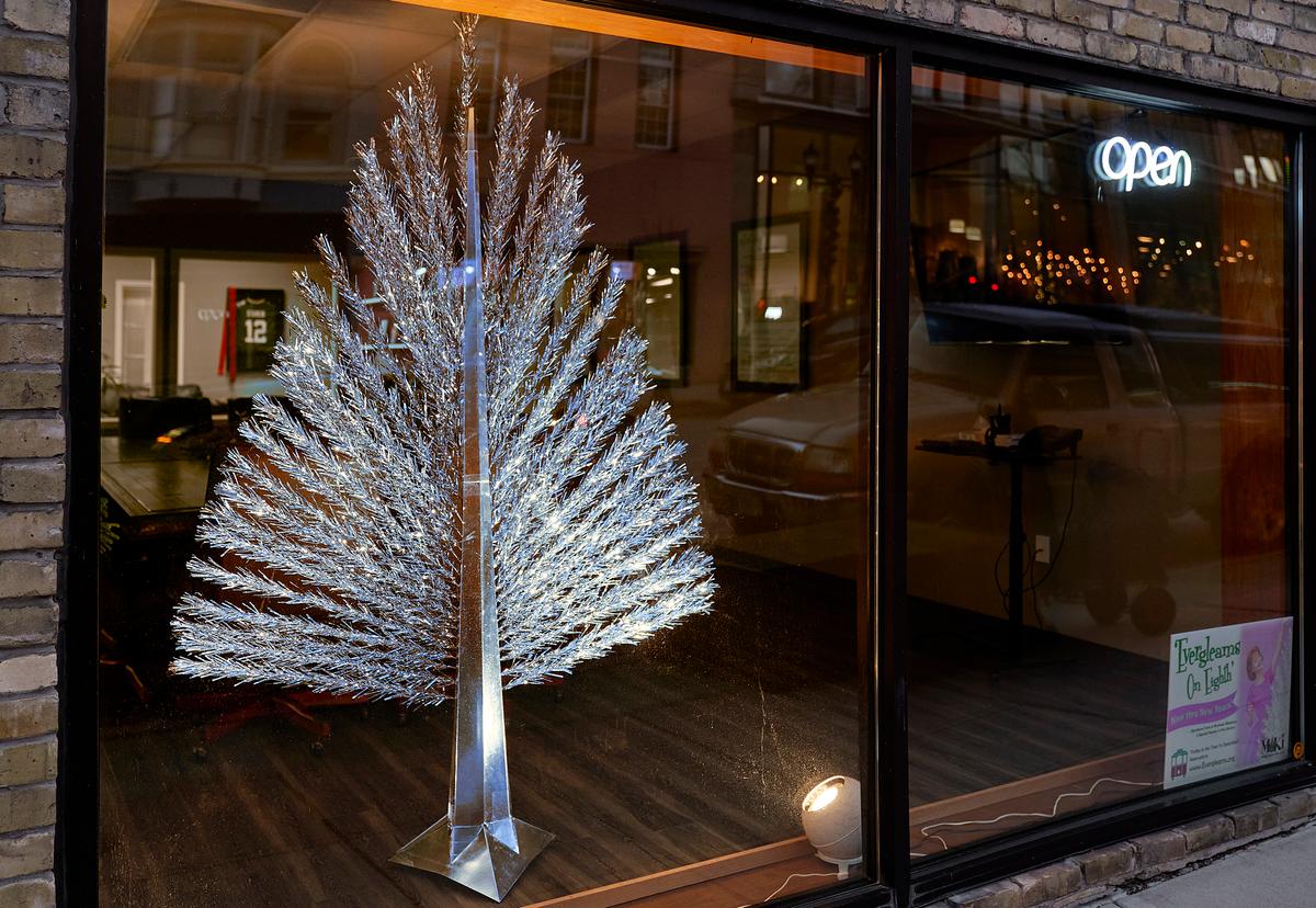 An aluminum tree gleams in a storefront in Manitowoc, Wis., on Dec. 6, 2021. A flat Christmas tree, designed by engineer Wesley Martin, was a space-saving alternative to bulkier trees. (Chris Duzynski/The Epoch Times)
