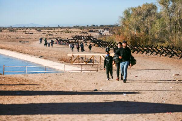Illegal immigrants walk toward the border fence to wait for Border Patrol after crossing from Mexico into the United States in Yuma, Ariz., on Dec. 10, 2021. (Charlotte Cuthbertson/The Epoch Times)