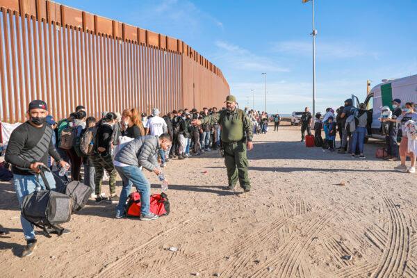 A Border Patrol agent organizes illegal immigrants who have gathered by the border fence after crossing from Mexico into the United States in Yuma, Ariz., on Dec. 10, 2021. (Charlotte Cuthbertson/The Epoch Times)