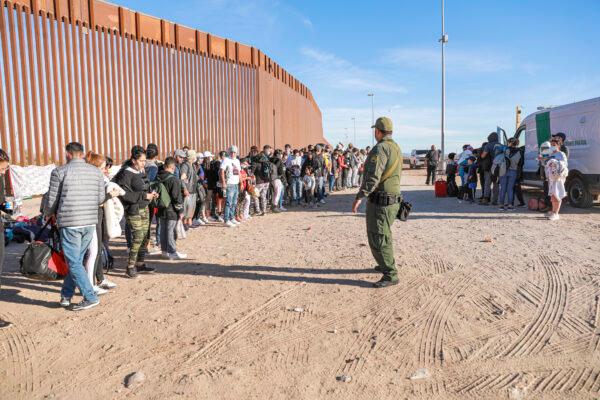 A Border Patrol agent organizes illegal immigrants who have gathered by the border fence after crossing from Mexico into the United States in Yuma, Ariz., on Dec. 10, 2021. (Charlotte Cuthbertson/The Epoch Times)