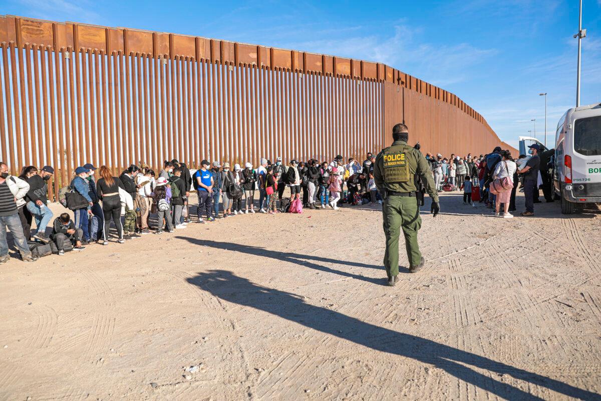 A Border Patrol agent organizes illegal immigrants who have gathered by the border fence after crossing from Mexico into the United States in Yuma, Ariz., on Dec. 10, 2021. (Charlotte Cuthbertson/The Epoch Times)