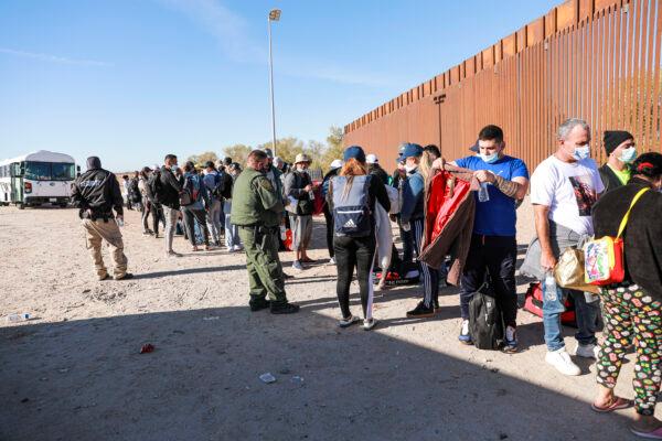A Border Patrol agent organizes illegal immigrants who have gathered by the border fence after crossing from Mexico into the United States in Yuma, Arizona, on Dec. 10, 2021. (Charlotte Cuthbertson/The Epoch Times)