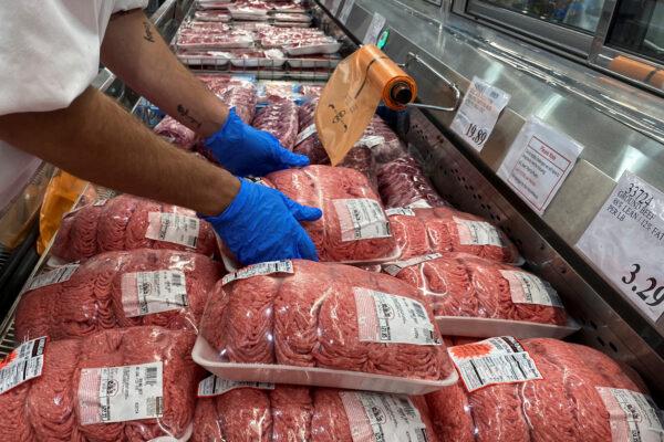 A worker stacks packets of ground beef in the meat section of a Costco warehouse club during the COVID-19 pandemic in Webster, Texas, on May 5, 2020. (Adrees Latif/Reuters)
