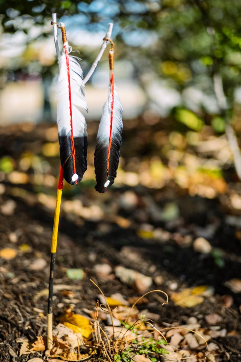 The designer of the memorial also left a ceremonial feather stick at the unofficial unveiling, silently striking the memorial four times before leaving it in the ground nearby. (Photo by Matailong Du for National Museum of the American Indian)